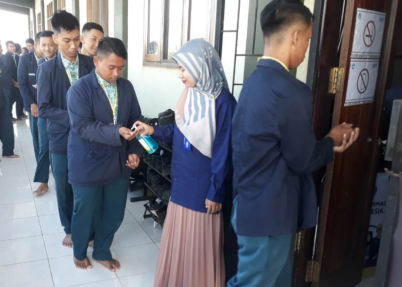Peserta UNBK SMK Muhammadiyah 3 Gresik membersih tangan dengan sanitizer sebelum memasuki kelas. (Hamdi/PWMU.CO)