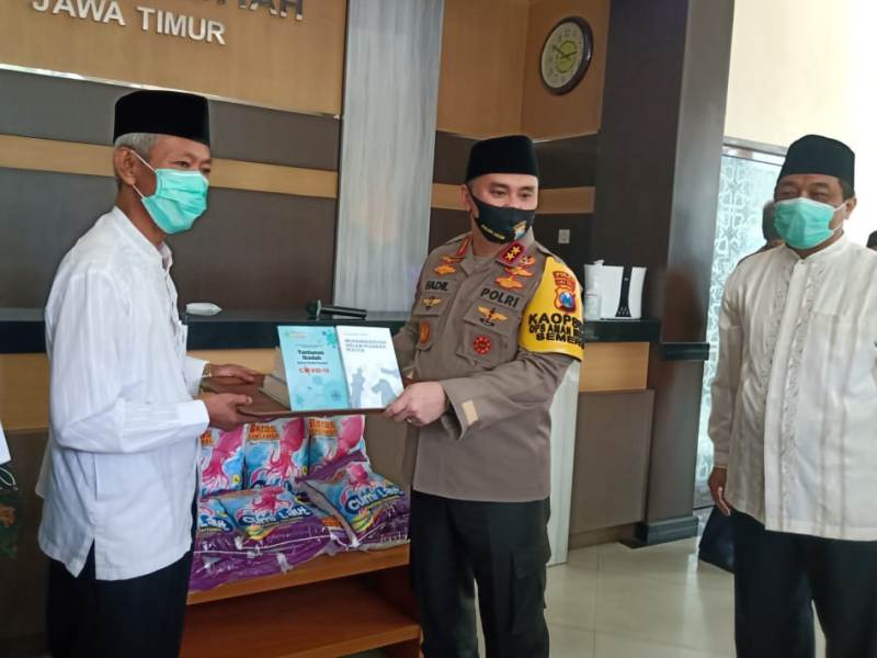 Ketua PWM Jatim Saad Ibrahim, kiri, menyerahkan buku kepada Kapolda Irjen Pol Fadil Imran. (Ilmi/PWMU.CO)