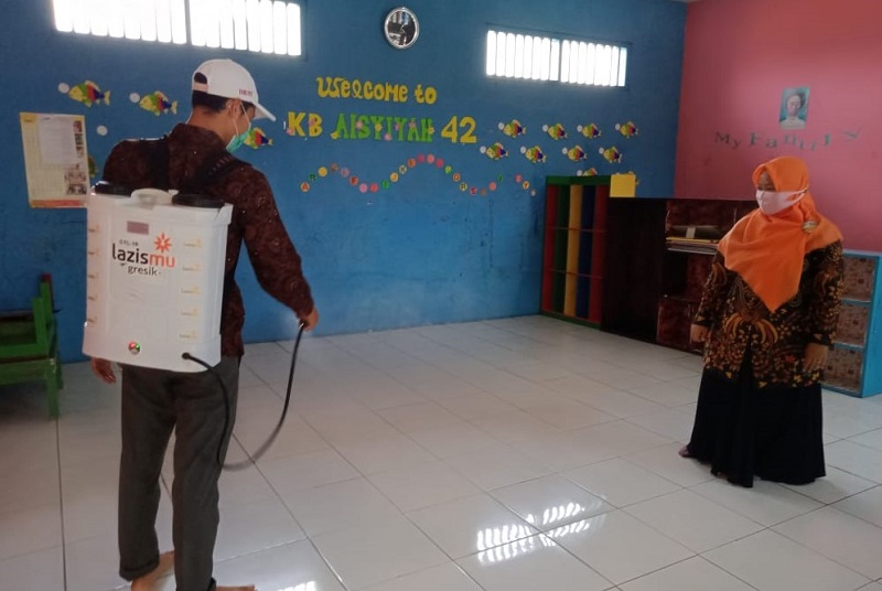 Almadany membantu menyemprot cairan disinfektan di lingkungan TK Aisyiyah Bustanul Athfal (ABA) 42 Graha Bunder Asri (GBA) Kembangan Kebomas Gresik, Senin (5/10/20).