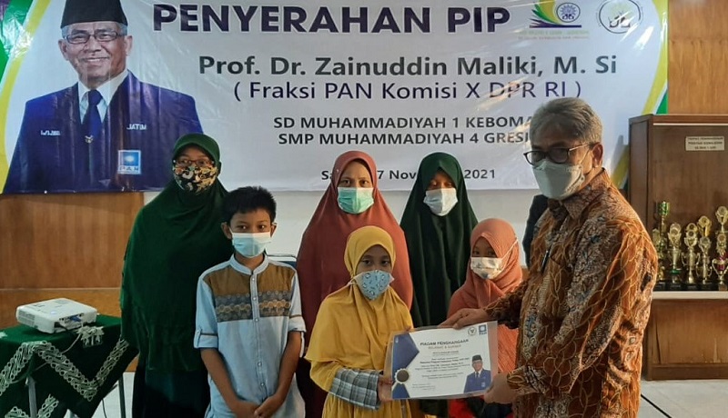 Prof Zainuddin Maliki MSi menyerahkan sertifikat beasiswa Program Indonesia Pintar (PIP) ke ssiswa SMP Muhammadiyah 4 dan SD Muhammadiyah 1 Giri Kebomas Gresik, Sabtu (27/11/21).