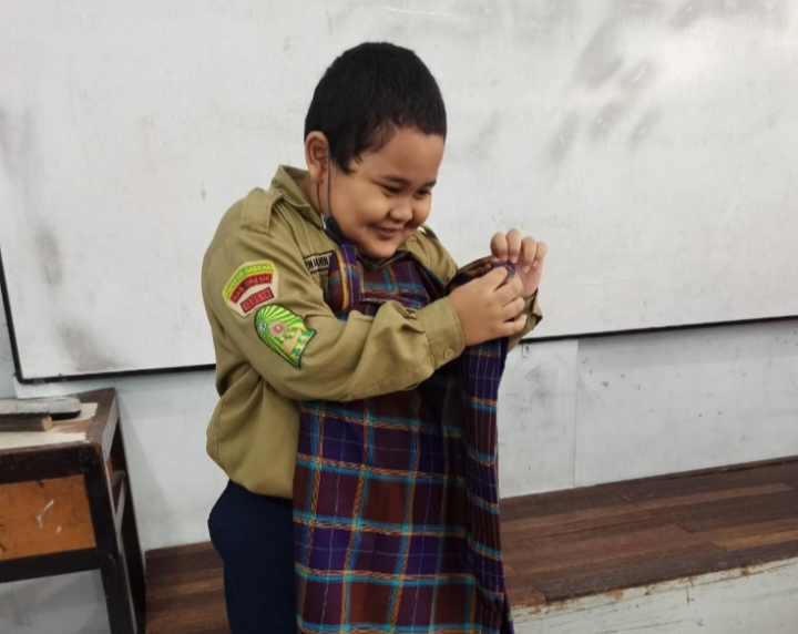 Siswa SD Mugeb M Syazwan Dahin Nebeel saat belajar melipat sarung di kelas (Madinah/PWMU.CO)