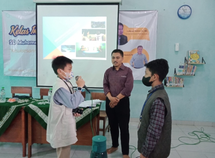 Mubaligh dan Wartawan Mengajar di Kelas Inspirasi SD Mudabo. Dua siswa sedang mengikuti Kelas Inspirasi, Rabu (19/10/2022) bersama wartawan Jawa Pos Radar Bojonegoro (Dian Yunita Sari/PWMU.CO)