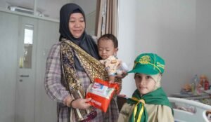 Fatimah Hilmi Baya'sud, murid kelas 1 SD Mugres Kampus A, memberikan paket perlengkapan mandi kepada keluarga pasien rawat inap RSMG (Indah Kurnia Safitri/PWMU.CO)