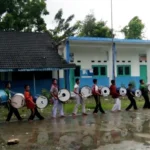 Dampingi Persiapan Santri, Ustadz Ini Rela Hujan-hujanan sambil Mainkan Alat Drum Band